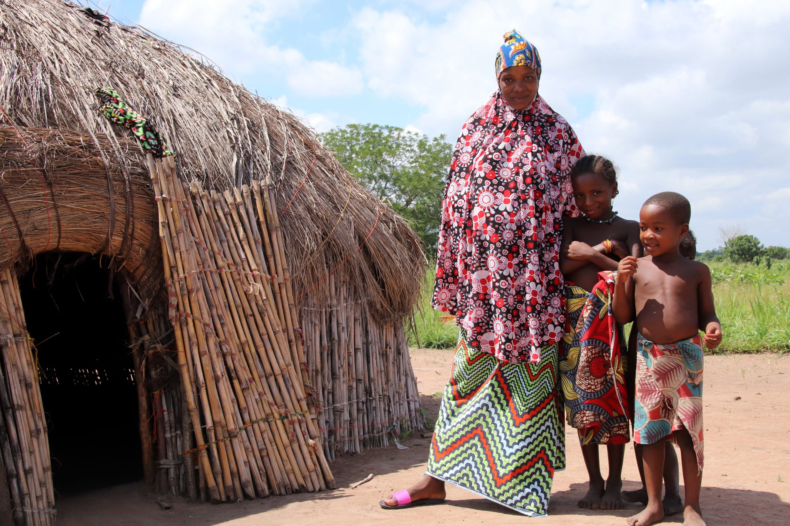 Atakpamé, Togo - June 29, 2019: Mother and her children at her house in a Fulani tribe village close Atakpamé, Togo, West Africa. The Fulani live closely with their animals in their village. The people live in straw huts with thatched roofs.